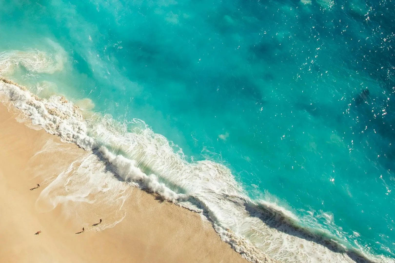 Stunning Bali beach with golden sand, turquoise waves, and swaying palm trees under a vibrant sunset sky.