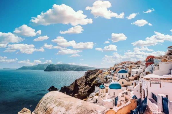 Panoramic view of Santorini's white-washed buildings and blue-domed churches overlooking the Aegean Sea, Greece.