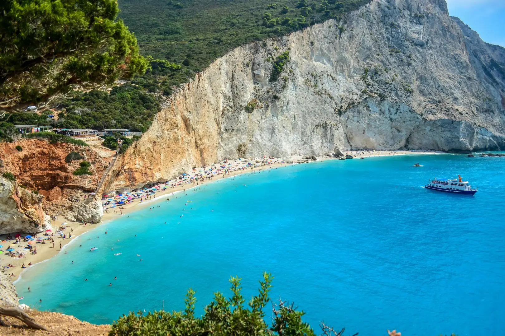 Scenic view of a Greek island with white-washed buildings, blue-domed churches, and the deep blue Aegean Sea in the background.